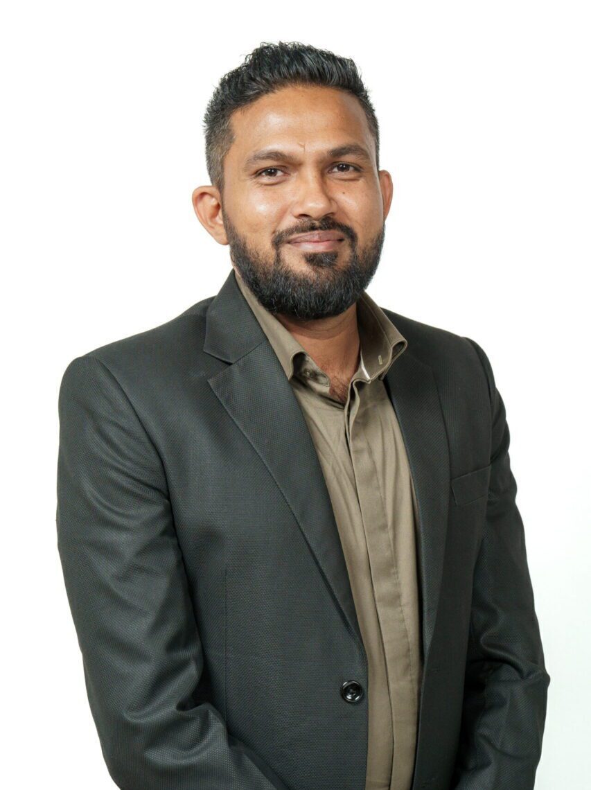 A smiling bearded man looking formal in a suit.