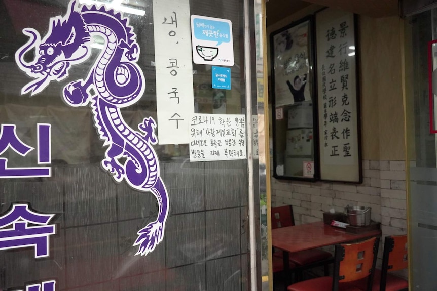 A sign stuck to a glass door with South Korean writing on it.