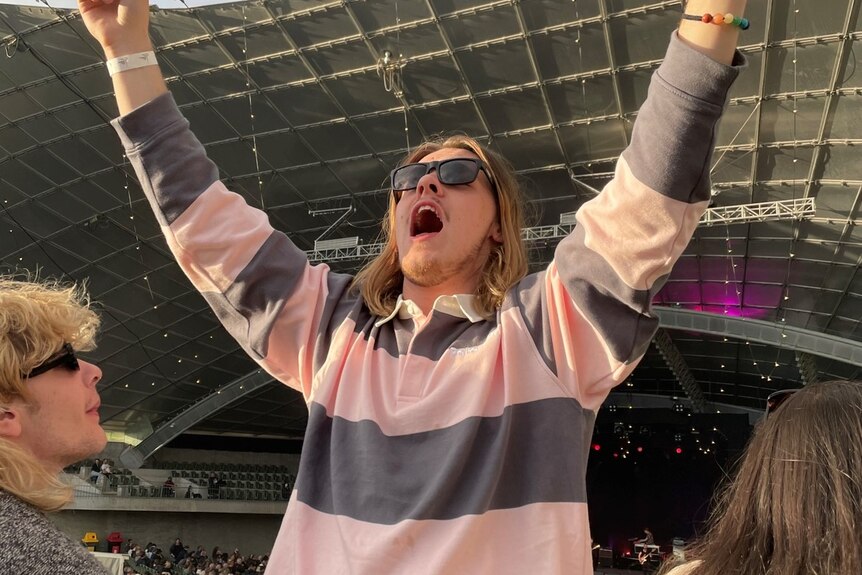 Jackson Lees cheering at a stadium with hands in the air
