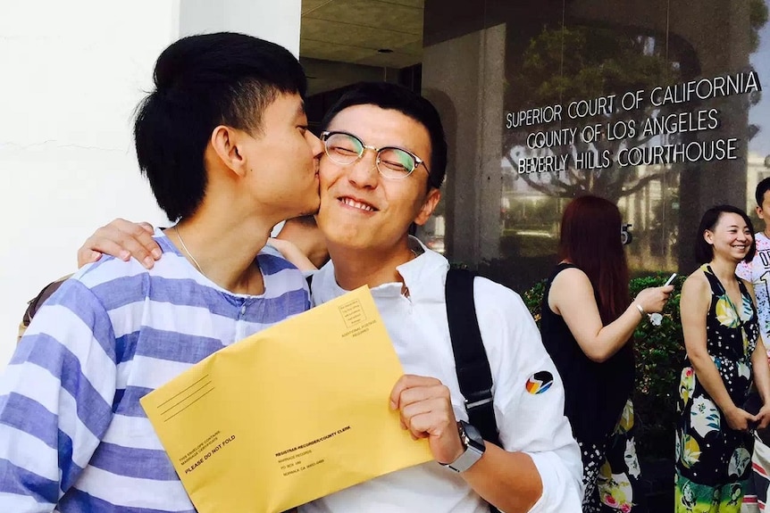 A man kisses his partner on the cheek as they hold marriage papers outside a court in LA.