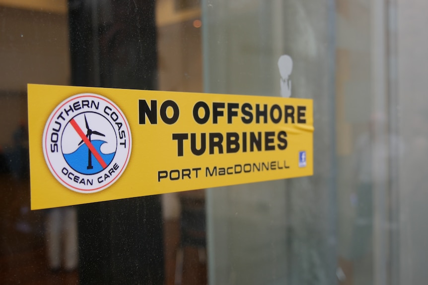 A yellow sticker which says "no offshore turbines" stuck to a window. 