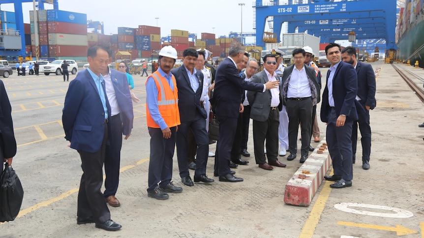 Men in suits stand at a port.