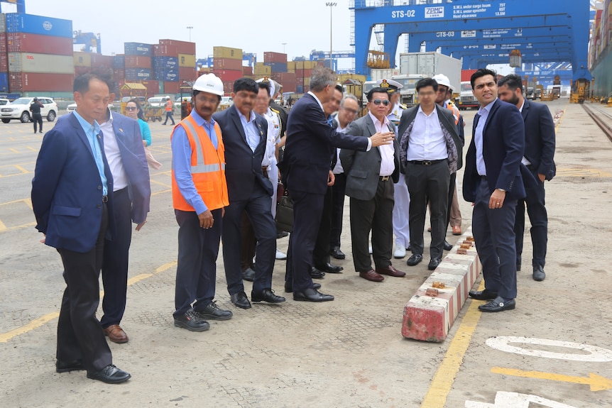 Men in suits stand at a port.