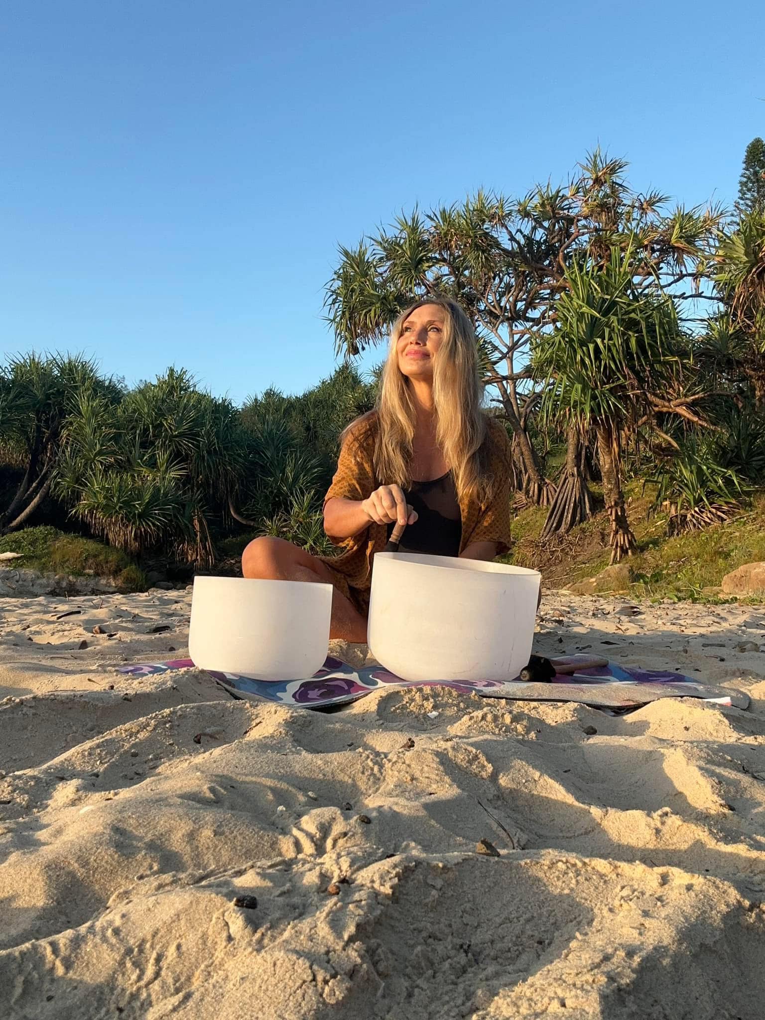 A woman sits on the beach with two cylinders in front of her.