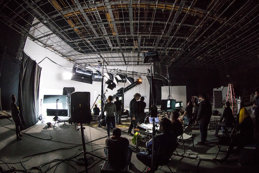 A film set with a number of people behind cameras and operating machinery 