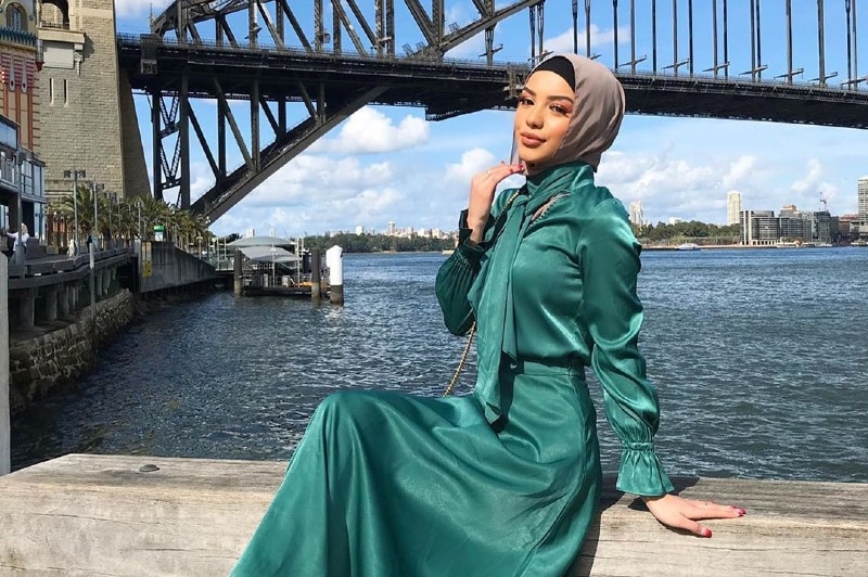 A woman in a pink hijab and silver dress.