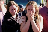 a woman puts her hand on another woman who is crying