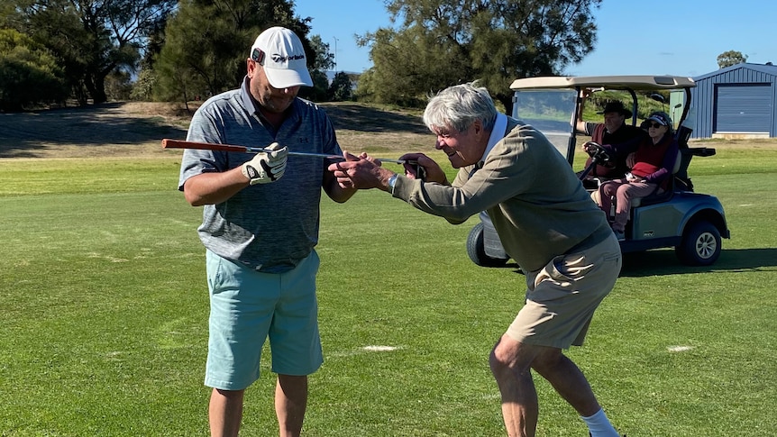 A vision-impaired golfer with a caddy lining up a shot.