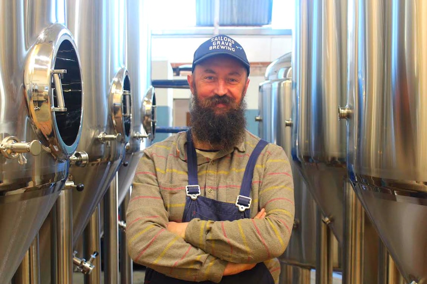 Chris Moore stands in front of a row of vats.