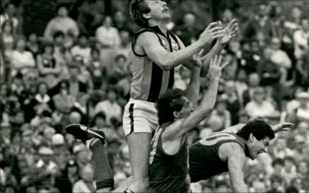A man jumps above a pack in the 1980s VFL