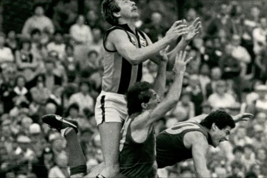 A man jumps above a pack in the 1980s VFL