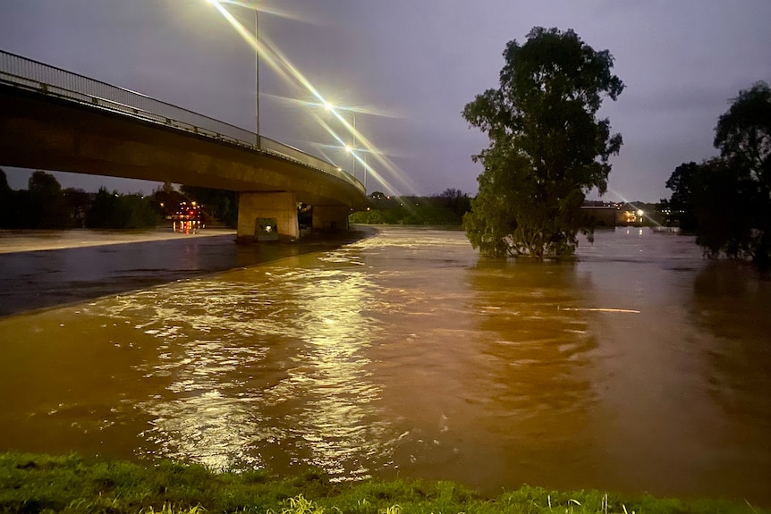 image of a flooded river, with water getting close to the top of a bridge.