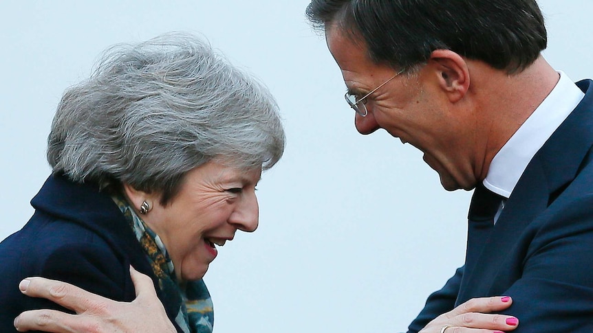 Theresa May smiles, leaning on Dutch PM Mark Rutte