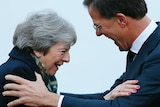 Theresa May smiles, leaning on Dutch PM Mark Rutte