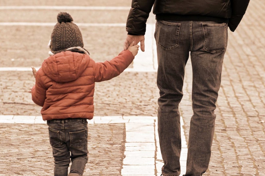 A man holds a child's hand.