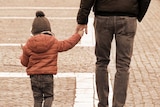 A man holds a child's hand.