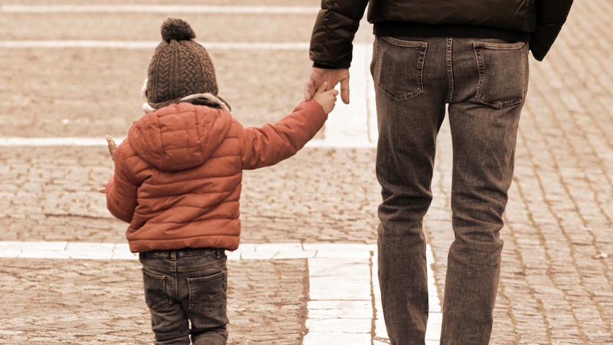 A man holds a child's hand.