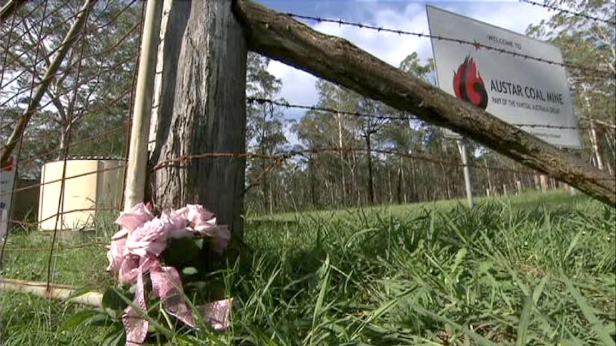 Flowers sit at the entrance to the Austar coal mine at Paxton, where two men died in a mine collapse.