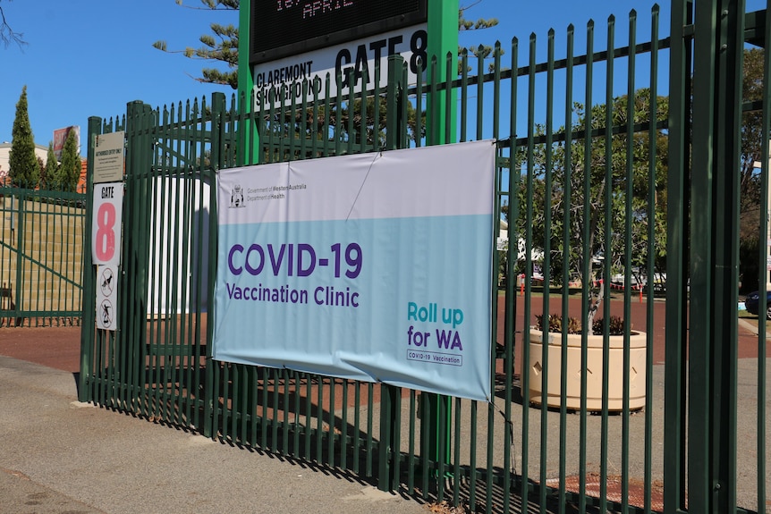 A big sign stating 'COVID-19 vaccination clinic' pinned to a gate at Claremont Showground