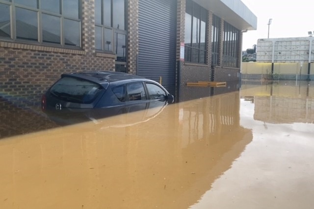 A car inundated in flood waters on a street.