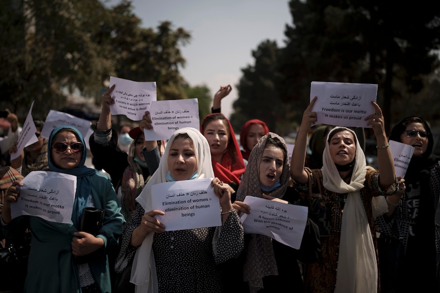 Mujeres caminando en Afganistán sosteniendo pancartas