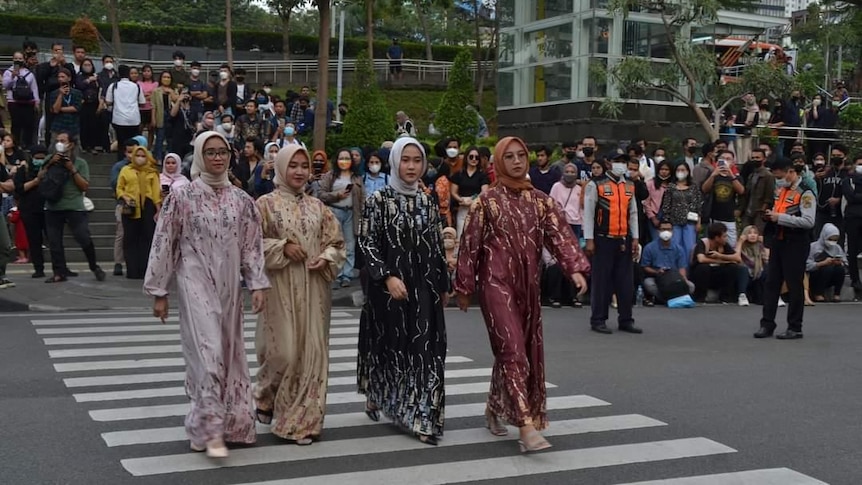 Four women wearing colorful hijabs walking through a zebra crossing.