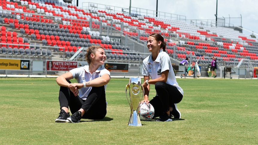 Jenna McCormick and Indiah-Paige Riley pose with the W-League trophy in a stadium