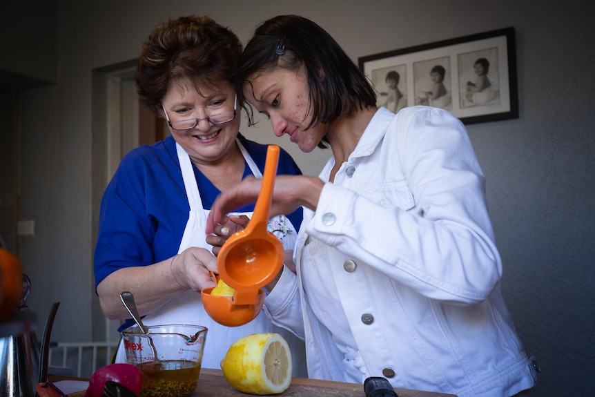 A young woman squeezing the juice from a lemon while another woman looks on