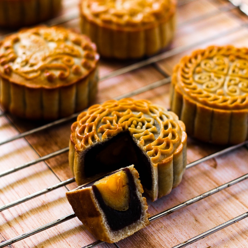 A moon cake with a cut quarter piece displayed.
