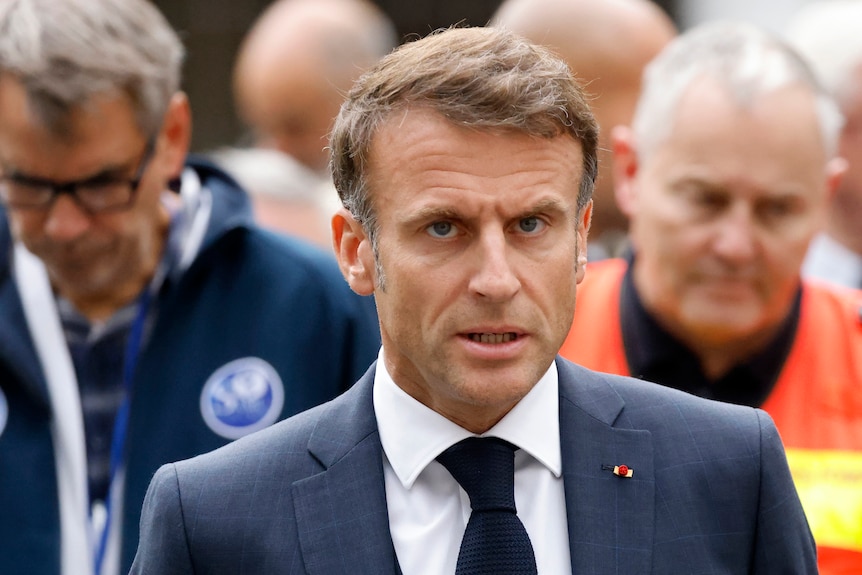 A close up image shows French President Emmanuel Macron as he talks to reporters.