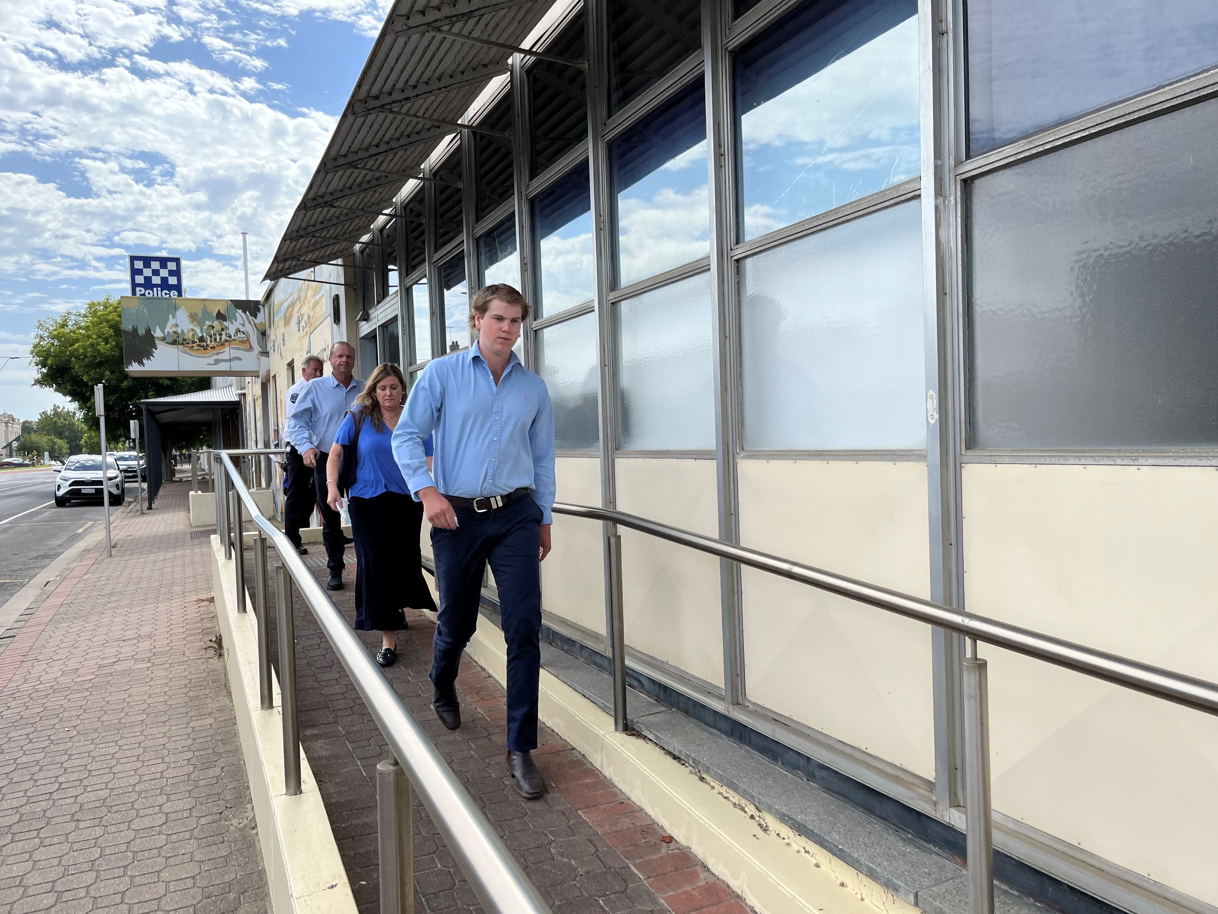 Two men and a woman leave a court building down a ramp