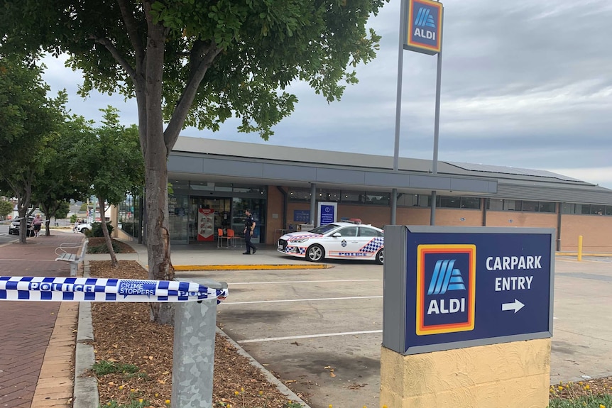 Police tape outside an Aldi store and a police officer near the entrance