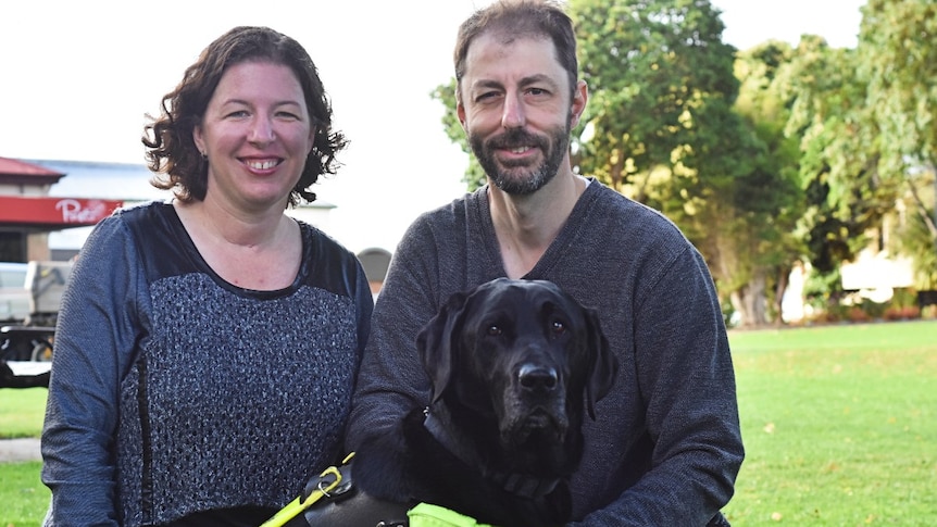 Man and woman with guide dog in park