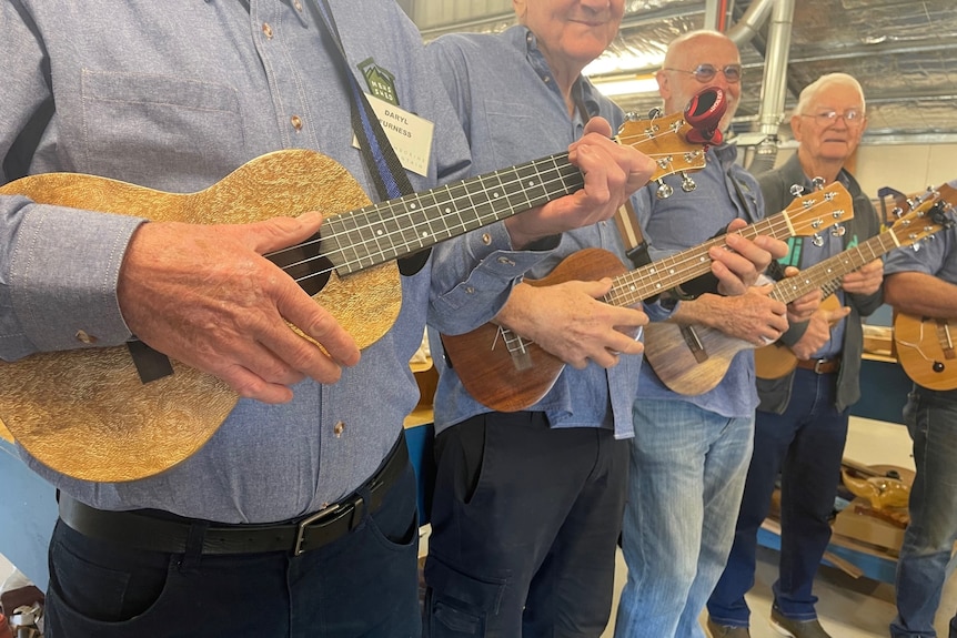 Men standing in a line playing handmade instruments.