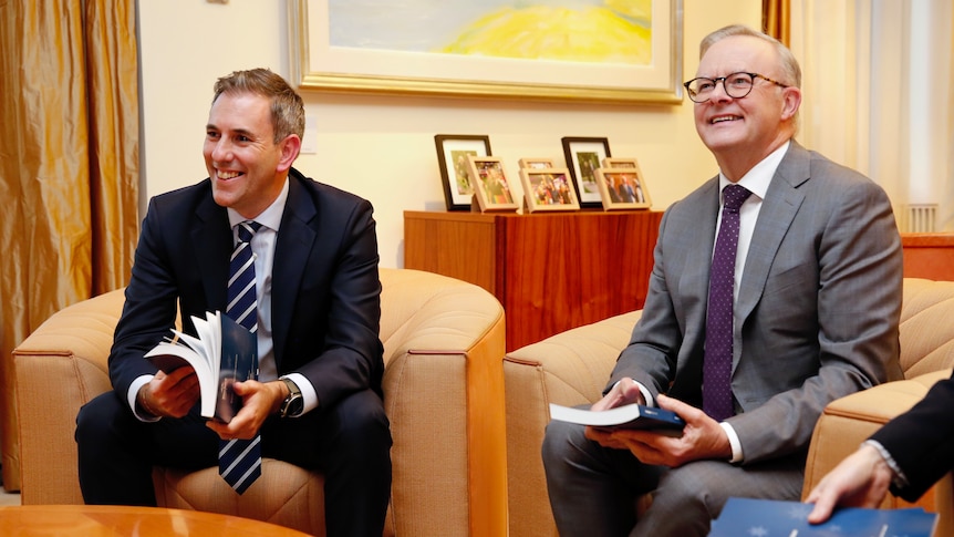 Chalmers and Albanese sit in lounges holding books and smiling.
