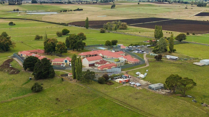A cluster of buildings and fencing in a green countryside seen from the air.