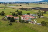 A cluster of buildings and fencing in a green countryside seen from the air.