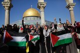 A group of protesters hold Palestinian flags and chant outside the al-Aqsa mosque in Jerusalem