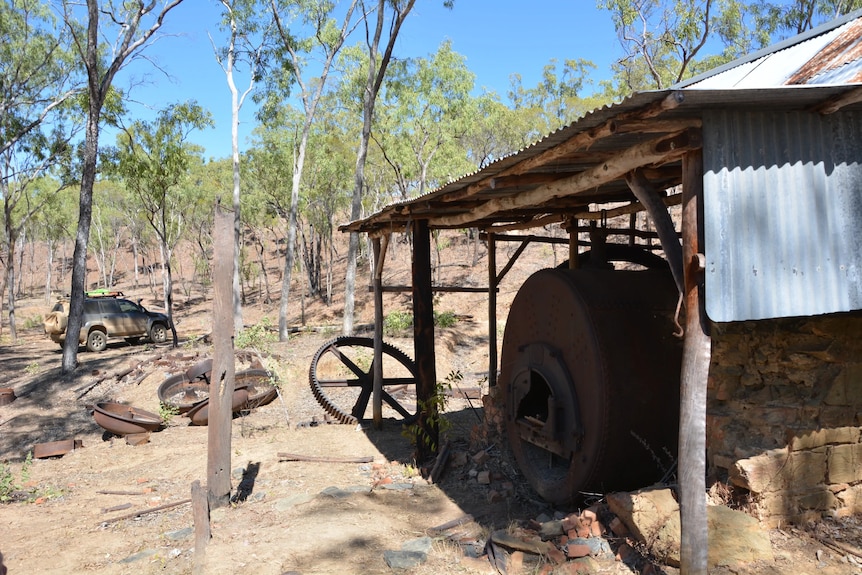An old shack in the bush with old equipment laying around it