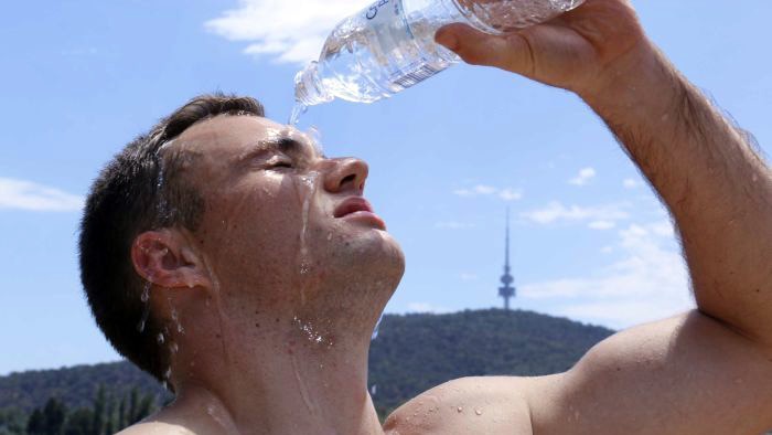 Man pours water on his head for some temporary relief from the heat.