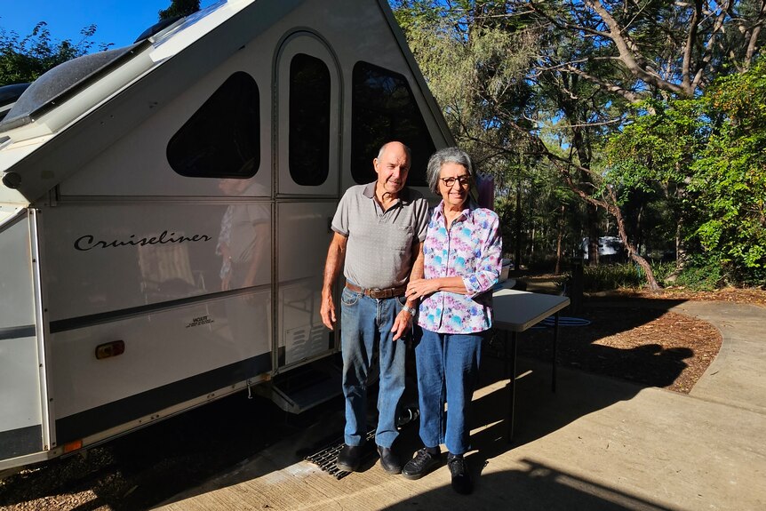 A woman and man in front of a caravan