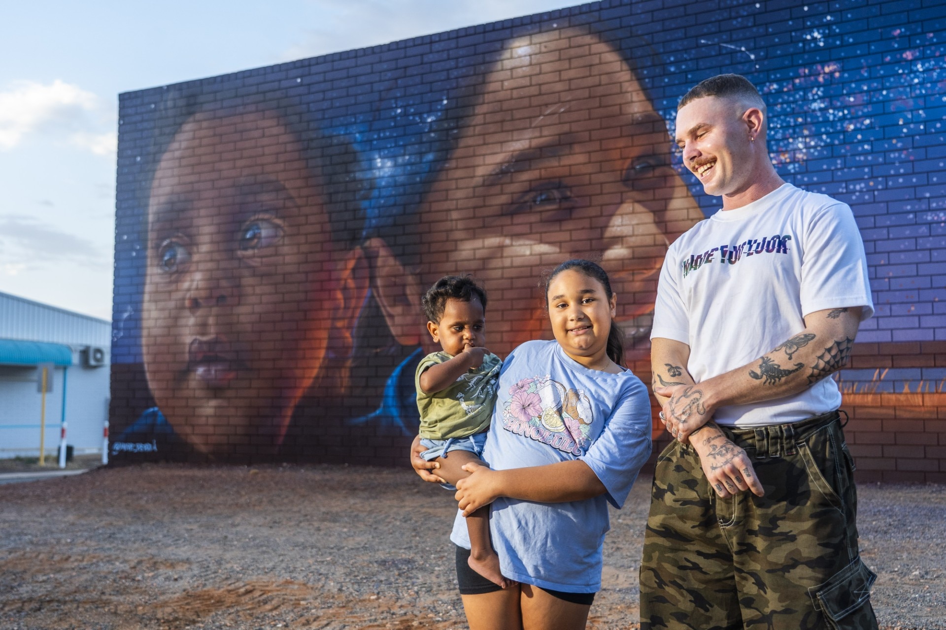 Uma família se reúne em frente a um mural pintado