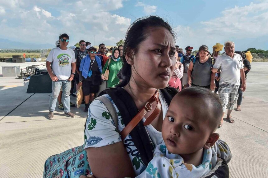 Mother and child wait to be evacuated in Indonesia