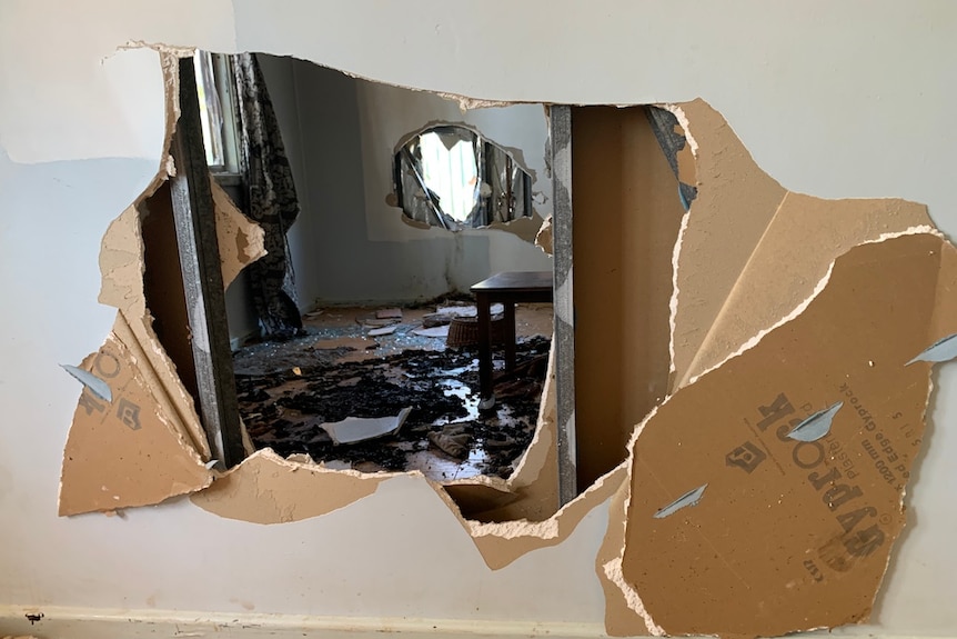 A hole smashed through a wall of a house.