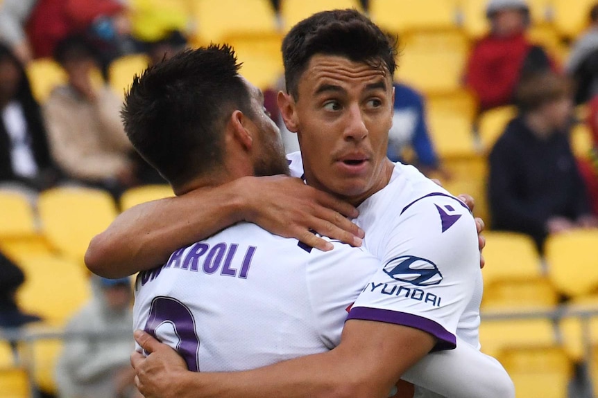 Two Perth Glory A-League players hug each other as they celebrate a goal scored against Wellington Phoenix.