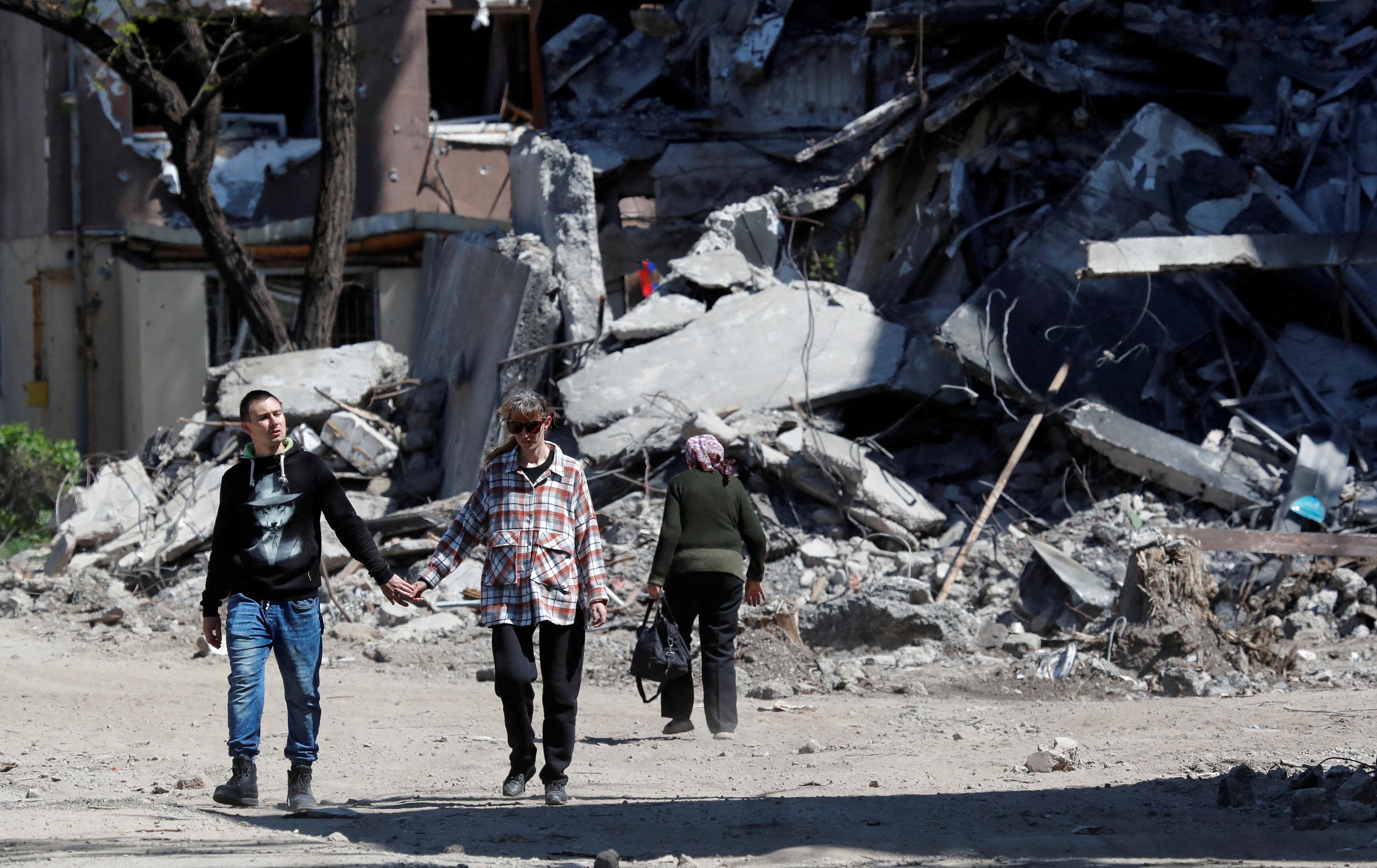People walk by destroyed building.