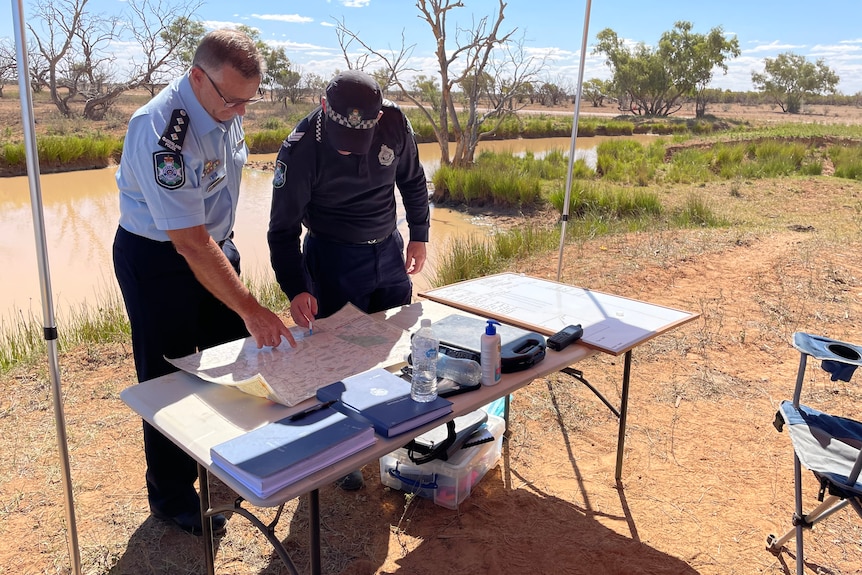Two police officers looking at a map under a canopy 