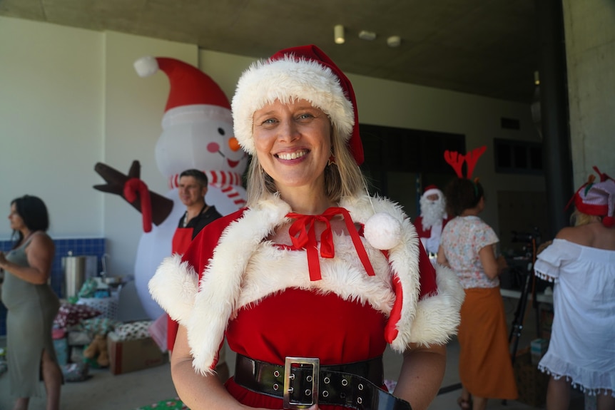A blonde woman smiles while dressed as Mrs Claus