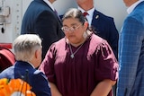 Mandy Gutierrez is dressed in a maroon top speaking with Texas Governor Greg Abbott who has his back to the camera.