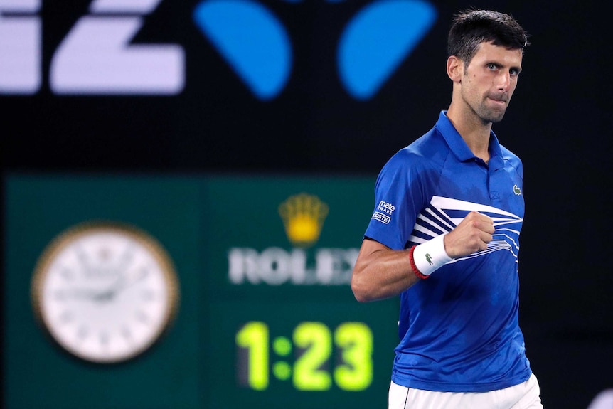 Novak Djokovic pumps his first with the centre court clock in the background.